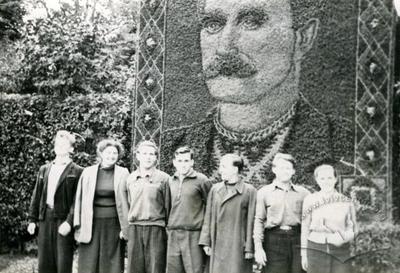 Група молоді на фоні панно з квітів у парку Костюшка