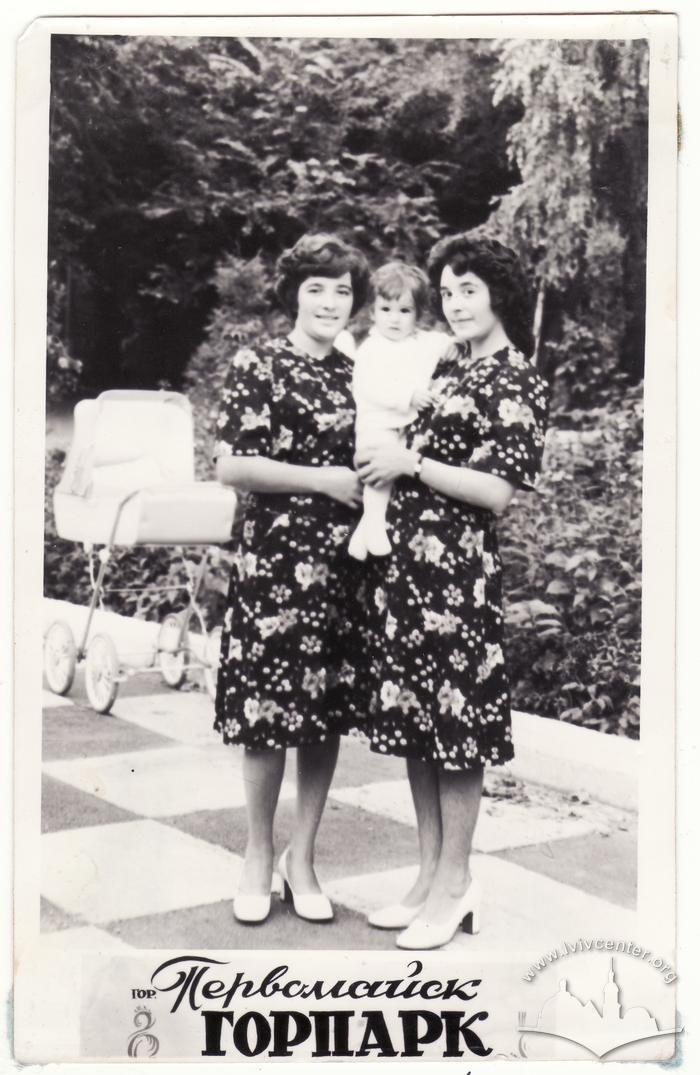 Two young women holding a child in a park 2