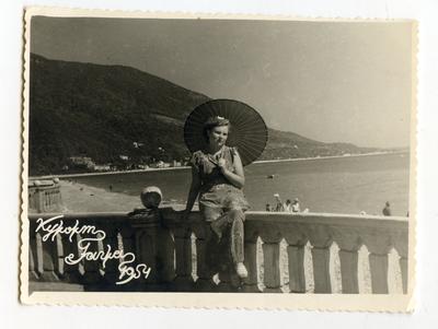 Woman with an umbrella with seaside behind